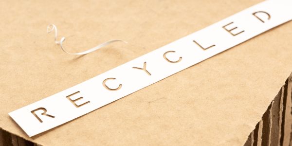Recycled paper or cardboard concept. Die cut label of paper with text Recycled on brown cardboard